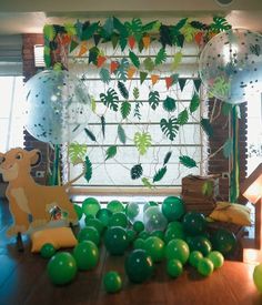 balloons and streamers are on the floor in front of a window with jungle decorations