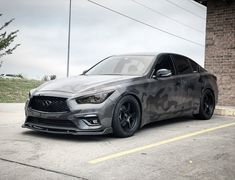 a gray car parked in front of a brick building with black rims and wheels