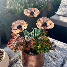 an arrangement of flowers in a pot on a patio table next to a couch and coffee table