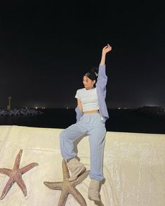 a woman standing on top of a starfish shaped wall with her arms in the air