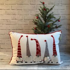 a christmas pillow sitting on top of a wooden table next to a small fir tree