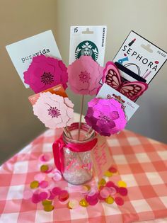 there are paper flowers in a mason jar on the checkered tablecloth with starbucks card holders