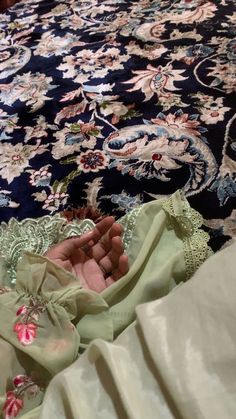 a baby laying on top of a bed next to a blue and white rug with pink flowers