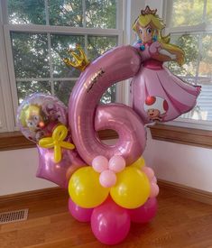 a large number six balloon sitting on top of a wooden floor in front of a window