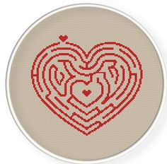 a cross stitch heart with two hearts in the center on a beige background, surrounded by smaller red hearts