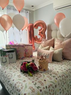 a bed topped with lots of balloons next to a table filled with cake and presents