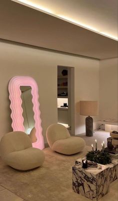 a living room filled with furniture and a large pink mirror on the wall above it