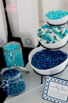 three bowls filled with blue candies on top of a table next to other items