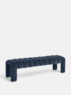 a blue bench that is sitting in the middle of a white wall and it's legs are bent down