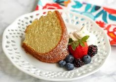 a piece of cake on a white plate with berries and whipped cream next to it