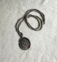 You will receive this fun faux coin pensant on a 24" chain.  It measures 1 7/8" x 1 1/4" and has a 4 mm bail opening.  The necklace is cast in a silver tone base metal and it is unbranded.  It is in good preowned wearable condition with minimal signs of wear. We have rebranded, and since December 2023 we are Lazy Frog Thrifters.  We have been flipping high end home decor that we find at thrift stores, yard sales, flea markets, and estate sales.  Come check out the old and tired items that we have given a French Country look or Cottage Core vibe to at:  https://lazyfrogthrifters.etsy.com Nickel Free Silver Medallion Necklace, Collectible Silver Metal Locket Necklace, Vintage Medallion Silver Chain Jewelry, Silver Medallion Locket Necklace, Vintage Silver Dog Tag Necklace, Vintage Silver Medallion Metal Necklace, Vintage Silver Medallion Necklace, Silver Coin-shaped Medallion Necklace, Silver Coin Pendant Medallion Necklace