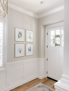 an entryway with white paneling and pictures on the wall