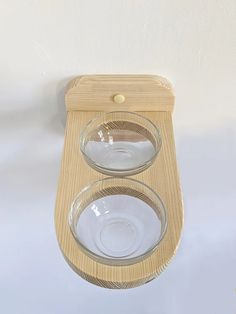 two bowls are sitting on top of a wooden holder that is attached to the wall