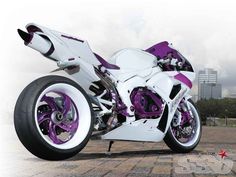 a white and purple motorcycle parked on top of a brick road