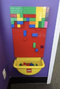 a lego wall mounted to the side of a purple wall next to a yellow sink