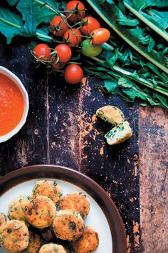 some food is on a plate next to tomatoes and greens