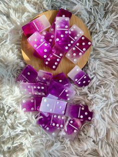 purple and white dice sitting on top of a wooden plate