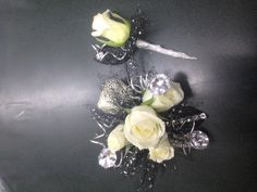 two white roses are sitting next to each other on a black table with silver sequins