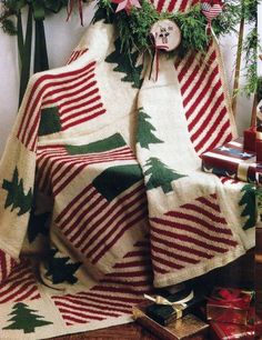 a christmas tree is wrapped in red and white knitted blankets with green trees on them