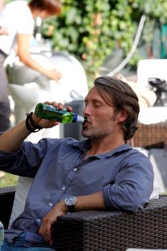 a man is drinking from a green bottle