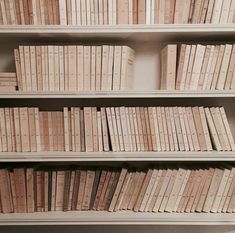 a bookshelf filled with lots of white books next to a wall mounted clock