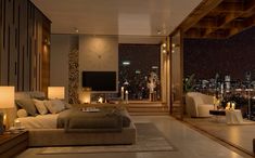 a living room with a large window overlooking the city at night and lit candles on the floor