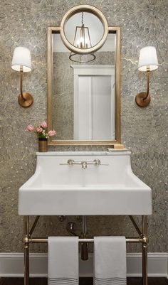 a white sink sitting under a mirror next to a wall mounted faucet in a bathroom