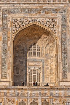 people are standing at the entrance to an ornate building with intricate carvings on it's walls