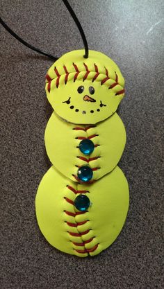 three yellow baseball ornaments with blue balls on them