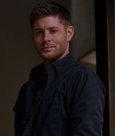 a man standing in front of a door wearing a black shirt