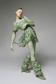 a woman is dressed in green and white polka dot print clothing, with her hands on her hips