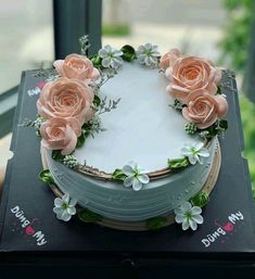 a cake decorated with pink roses and greenery