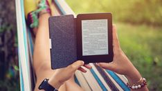 a person laying in a hammock reading a book on an electronic tablet computer