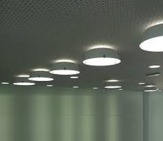 several round lights are hanging from the ceiling in an empty room with white walls and green curtains