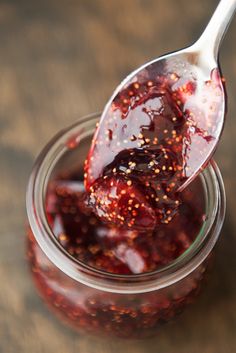 a spoon full of jam sitting on top of a wooden table