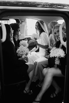 a group of bridesmaids sitting in the back of a car with their bouquets