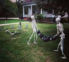 two skeletons are in the yard, one is laying on his back and another is lying down