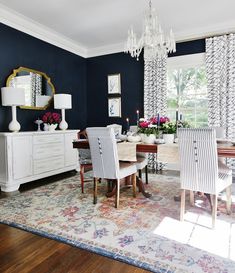 the dining room is decorated in blue and white with striped chairs, chandelier, and rug