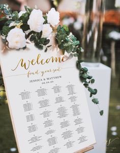 a sign with flowers and greenery on it that says welcome to the wedding guests