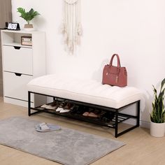 a white bench with shoes underneath it and a handbag on the floor next to it