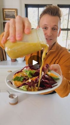 a man pouring dressing onto a plate of salad