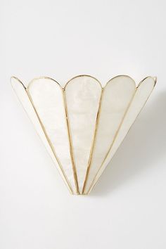 an art deco fan shaped object on a white surface with gold trimmings and curved edges