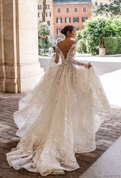 a woman in a wedding dress is standing on the street with her back to the camera