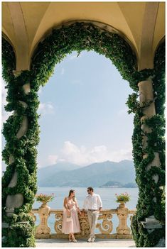 a man and woman standing under an archway