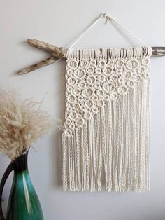 a white wall hanging next to a green vase