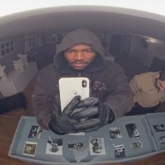 a man in a hoodie is looking at his cell phone while sitting on a table