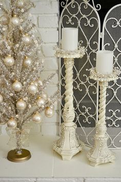 a white christmas tree and two candles on a mantle