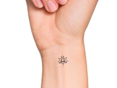 a woman's wrist with a small lotus tattoo on the left side of her arm