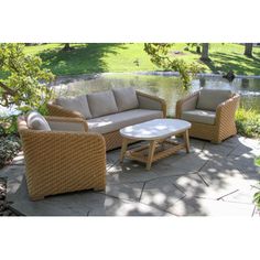 an outdoor patio furniture set sitting on top of a stone walkway next to a pond