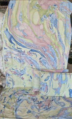 an upholstered chair is covered in multicolored marbled paper and fabric